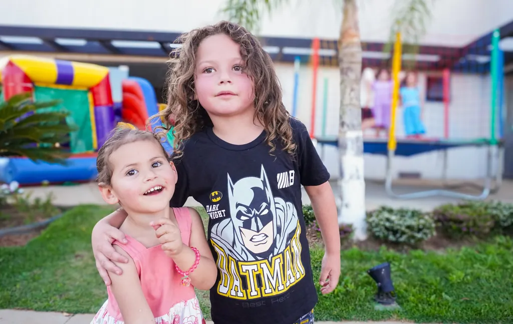 Dois irmãos abraçados em uma festa infantil ao ar livre
