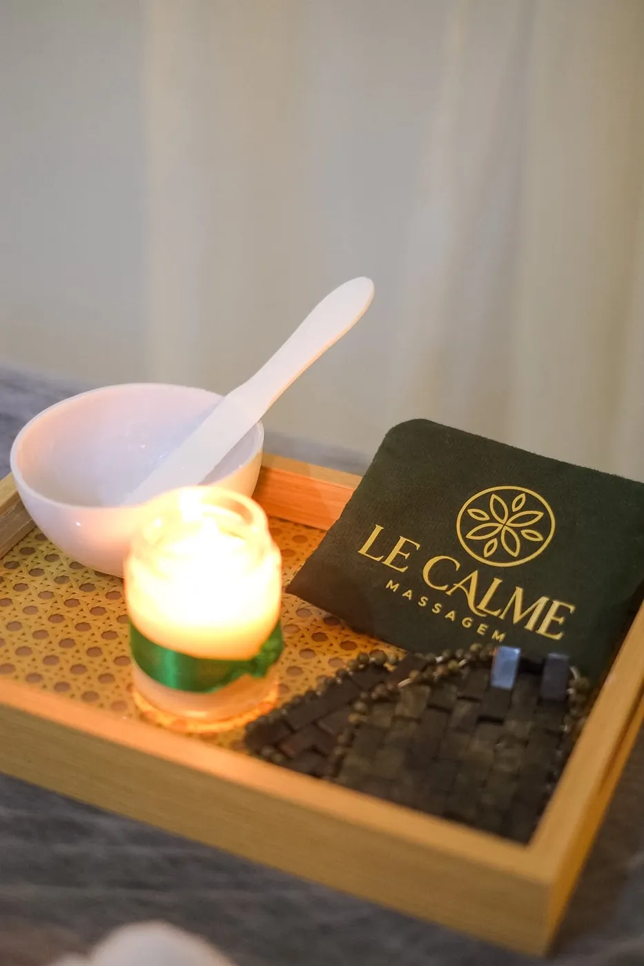 Bandeja com vela acesa, tigela e bolsinha com a marca Le Calme Massagem
