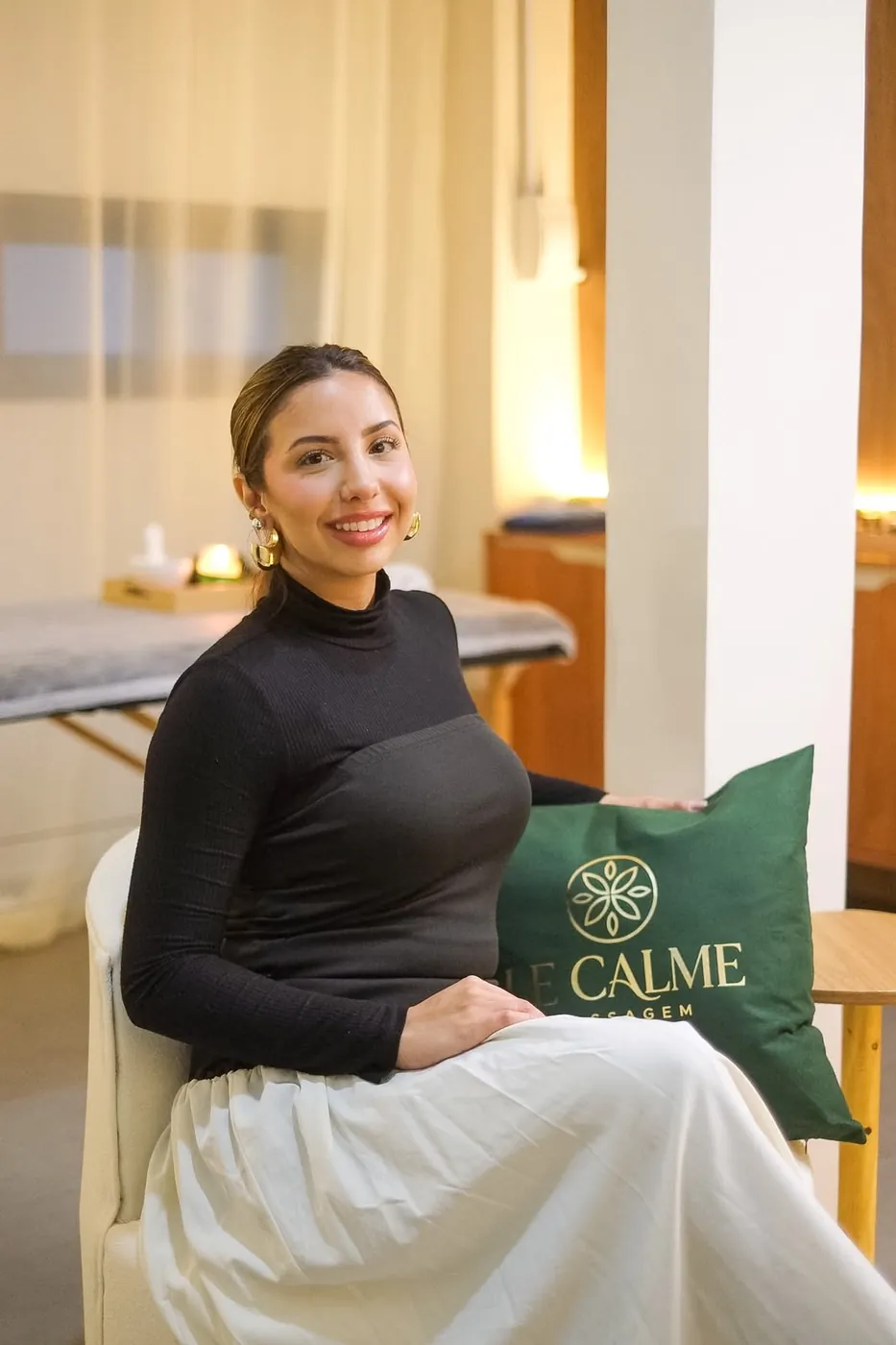 Profissional sentada na sala de atendimento, com a almofada verde da Le Calme ao lado